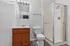 Modern bathroom featuring a sleek shower enclosure, elegant wooden vanity, and contemporary lighting fixtures.