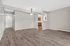 Bright living space featuring elegant wood flooring and modern lighting, leading into a cozy kitchen area with ample cabinetry.