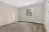 Bright, spacious room with elegant wood flooring and a large window offering a serene view of lush greenery.
