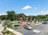 Scenic view of Park West Apartments surrounded by lush greenery and a spacious parking area under a clear blue sky.