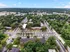 Aerial view of a vibrant apartment complex surrounded by lush greenery, showcasing ample parking and peaceful tree-lined streets.