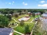 Scenic aerial view of a vibrant apartment complex with a refreshing swimming pool, surrounded by lush greenery and charming pathways.