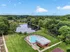 Scenic aerial view of a tranquil apartment complex featuring a heart-shaped pool, lush greenery, and a serene pond.