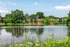 Serene apartment complex nestled by a tranquil lake surrounded by lush greenery, offering picturesque water views.