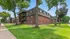Charming apartment building nestled in lush greenery with elegant brick facade, offering serene and comfortable living.