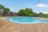 Inviting outdoor pool area surrounded by lush greenery and contemporary apartments, featuring comfortable blue lounge chairs and a serene atmosphere.