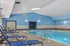 Inviting indoor pool area with stylish blue lounge chairs and modern skylights, perfect for relaxation and leisure.