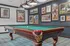 Chic game room featuring an elegant pool table, vintage art on deep blue walls, and stylish lighting.