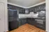 Elegant kitchen with sleek black cabinetry, modern appliances, and warm wood flooring for a contemporary living space.
