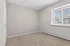 Bright and inviting room featuring plush carpet, natural light through a large window, and a spacious wardrobe.