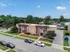Charming aerial view of a stylish brick apartment complex surrounded by lush greenery and ample parking, set in a peaceful residential neighborhood.
