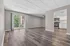 Beautiful open living area with elegant wood flooring, modern ceiling fan, and sliding glass doors leading to a private balcony. Bright kitchen with stainless steel appliances and ample white cabinetry.