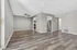 Modern apartment interior showcasing open living space with elegant wood flooring, stylish ceiling fan, and a sleek kitchen entrance with stainless steel refrigerator.