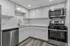 Modern kitchen with sleek stainless steel appliances, elegant white cabinetry, and stylish wood flooring.