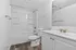 Elegant bathroom featuring a modern vanity with polished fixtures, pristine bathtub with integrated shelving, and stylish wood-look flooring.