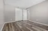 Modern bedroom with sleek laminate flooring, neutral walls, and spacious closet space.