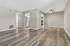 Modern living area featuring elegant hardwood flooring, a sleek ceiling fan, and an open entrance to a stainless steel equipped kitchen.