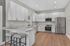 Modern kitchen with sleek white cabinetry, stainless steel appliances, and inviting bar seating on elegant wood flooring.
