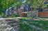Charming brick apartment complex with balconies, nestled among lush greenery and trees, offering a serene living environment.