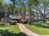 Charming apartment building with vibrant landscaping, spacious balconies, and a welcoming pathway under lush green trees.