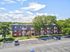 Charming apartment complex surrounded by lush greenery, showcasing spacious balconies and ample parking under a vibrant blue sky.