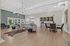 Modern open-concept living space with elegant chandelier, cozy gray sofa, stylish dining area, and lush outdoor views.