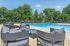 Inviting outdoor pool area with stylish lounge seating surrounded by lush green trees and a clear blue sky.