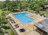 Inviting outdoor pool area surrounded by lush greenery, featuring ample lounge chairs and patio umbrellas for relaxation.