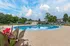 Inviting outdoor pool area surrounded by lush greenery and lounge chairs under a vibrant blue sky.