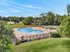 Inviting outdoor pool surrounded by lush greenery, offering a perfect relaxation spot with lounge chairs and scenic views.