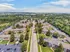 Aerial view of a vibrant residential community surrounded by lush greenery, showcasing multiple apartment buildings with ample parking and scenic landscapes.