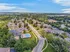 Scenic aerial view of a vibrant apartment community featuring lush green spaces, a sparkling swimming pool, and ample parking surrounded by natural landscapes.