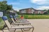 Inviting outdoor space featuring comfortable lounge chairs by the poolside, with a scenic view of modern apartment buildings and lush greenery.