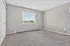 Bright and inviting empty room with plush carpet, neutral walls, and a large window with a serene view.