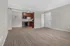 Inviting living space with plush carpet and modern open kitchen featuring sleek cabinetry and a built-in microwave.