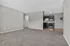 Spacious living area with plush carpeting and a sleek modern kitchen, offering a perfect blend of comfort and style.