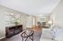 Cozy living room with elegant decor, soft beige walls, and warm wood flooring, featuring a comfortable sofa, stylish artwork, and a welcoming dining area.