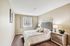 Inviting bedroom with a plush bed, elegant decor, and ample natural light through a large window.