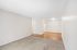 Bright living space with plush carpet, seamless transition to wood flooring, and modern lighting, ideal for welcoming comfort.