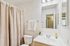 Bright and inviting bathroom with elegant fixtures, a large mirror, and a stylish beige shower curtain.