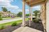 Inviting view from a cozy porch overlooking a beautifully landscaped suburban street, showcasing charming residences and lush greenery under a bright blue sky.