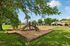 Charming playground set in a lush, green park with residential homes in the background, perfect for family-friendly living.