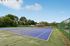 Inviting outdoor tennis court surrounded by lush greenery and clear blue skies, perfect for an active lifestyle.