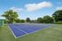 Vibrant outdoor tennis court surrounded by lush greenery, perfect for residents' recreational activities.