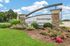 Inviting entrance of Stonebridge Luxury Apartments with lush landscaping and vibrant flowers, set against a bright blue sky.