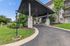Elegant apartment entrance with a modern canopy, surrounded by lush greenery and a well-maintained driveway.
