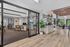 Modern open-concept office and lounge space with sleek glass partitions, stylish wooden flooring, and lush greenery accents.
