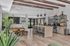 Contemporary open-concept living area with elegant wooden beams, sleek kitchen island, and lush green plants, offering a stylish and inviting atmosphere.