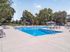 Luxurious outdoor swimming pool area with elegant lounge chairs and lush greenery, perfect for relaxation and leisure in a serene apartment community.