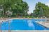 Inviting outdoor swimming pool surrounded by lush greenery and comfortable lounge chairs, perfect for relaxation and leisure.